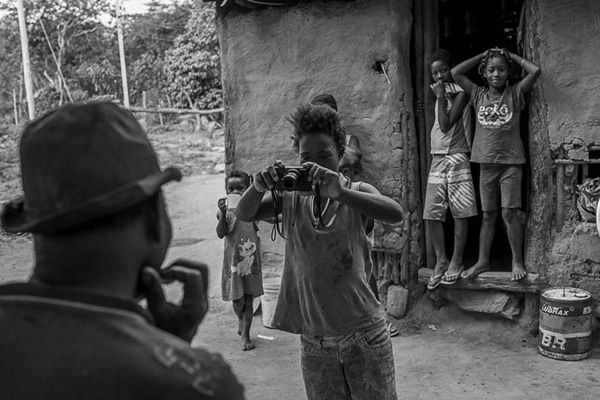 Foto em preto e branco, realizada em 2015, na Serra do Espinhaço, em Minas Gerais, que retrata moradores daquela comunidade fazendo fotografias uns dos outros