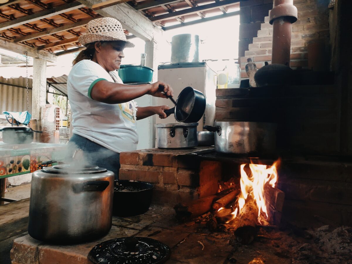 Uma mulher cozinha em um fogão a lenha