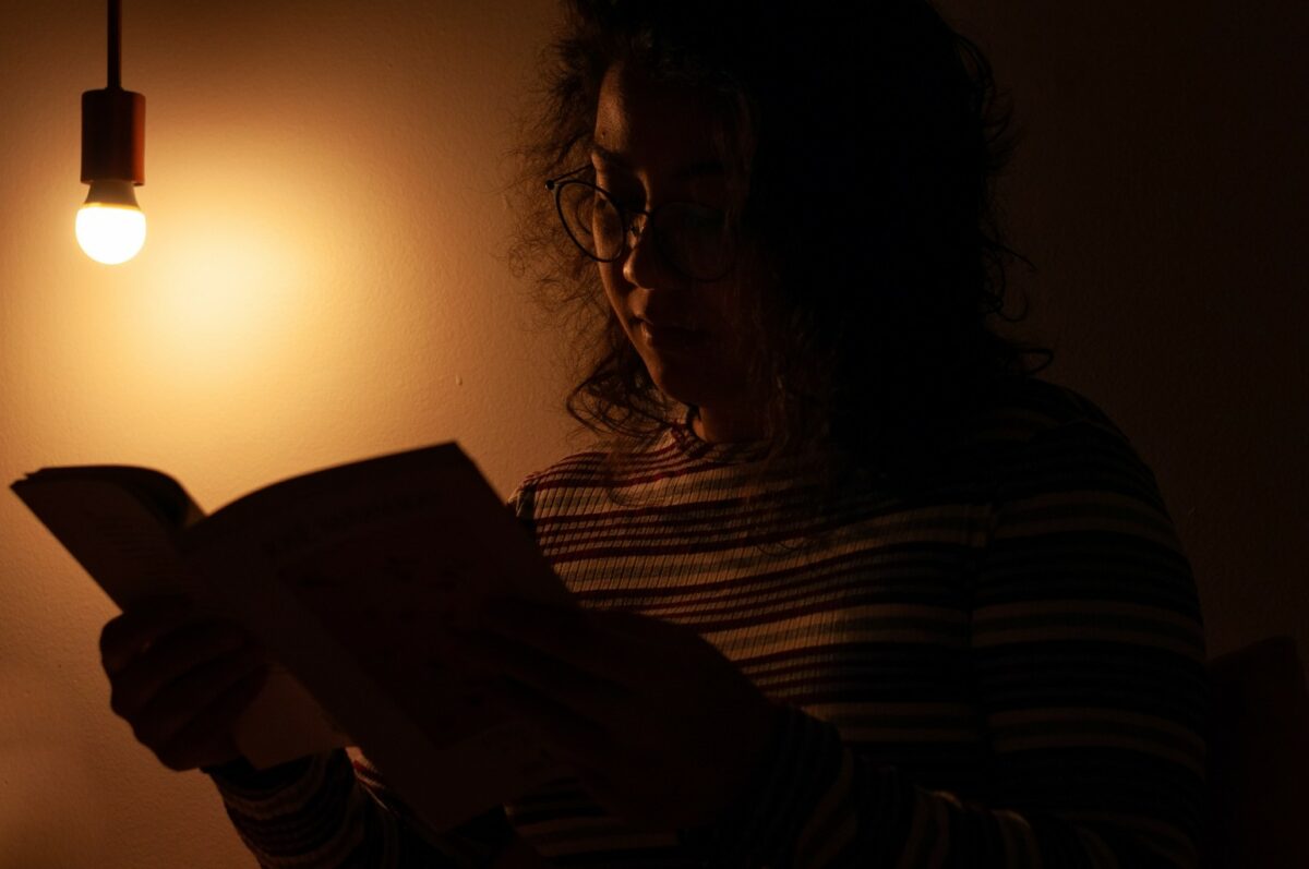 Mulher lê livro a meia-luz