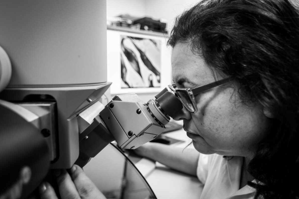 Cientista em um laboratório olhando através de um aparelho que se assemelha a um microscópio