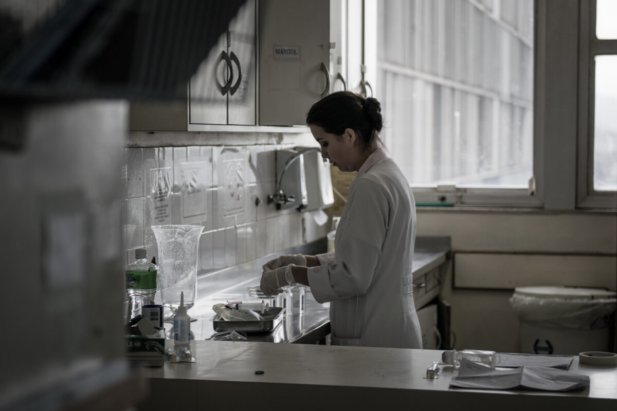 Mulher com jaleco e luvas trabalha em um laboratório