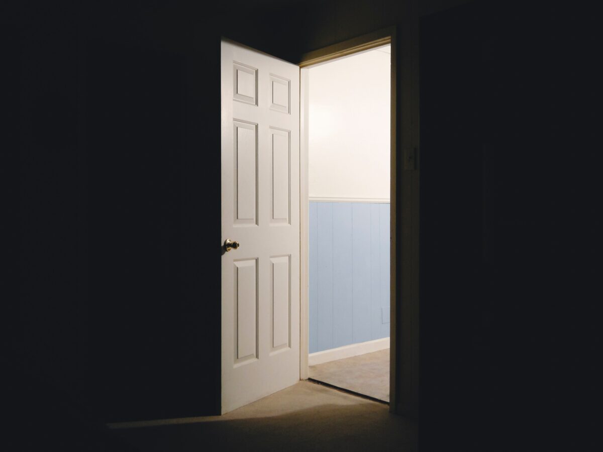 Imagem de um porta aberta de um ambiente escuro para outro claro