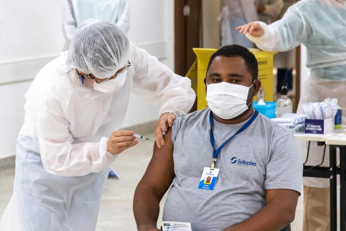 Enfermeira paramentada com equipamento de proteção individual vacina homem de máscara