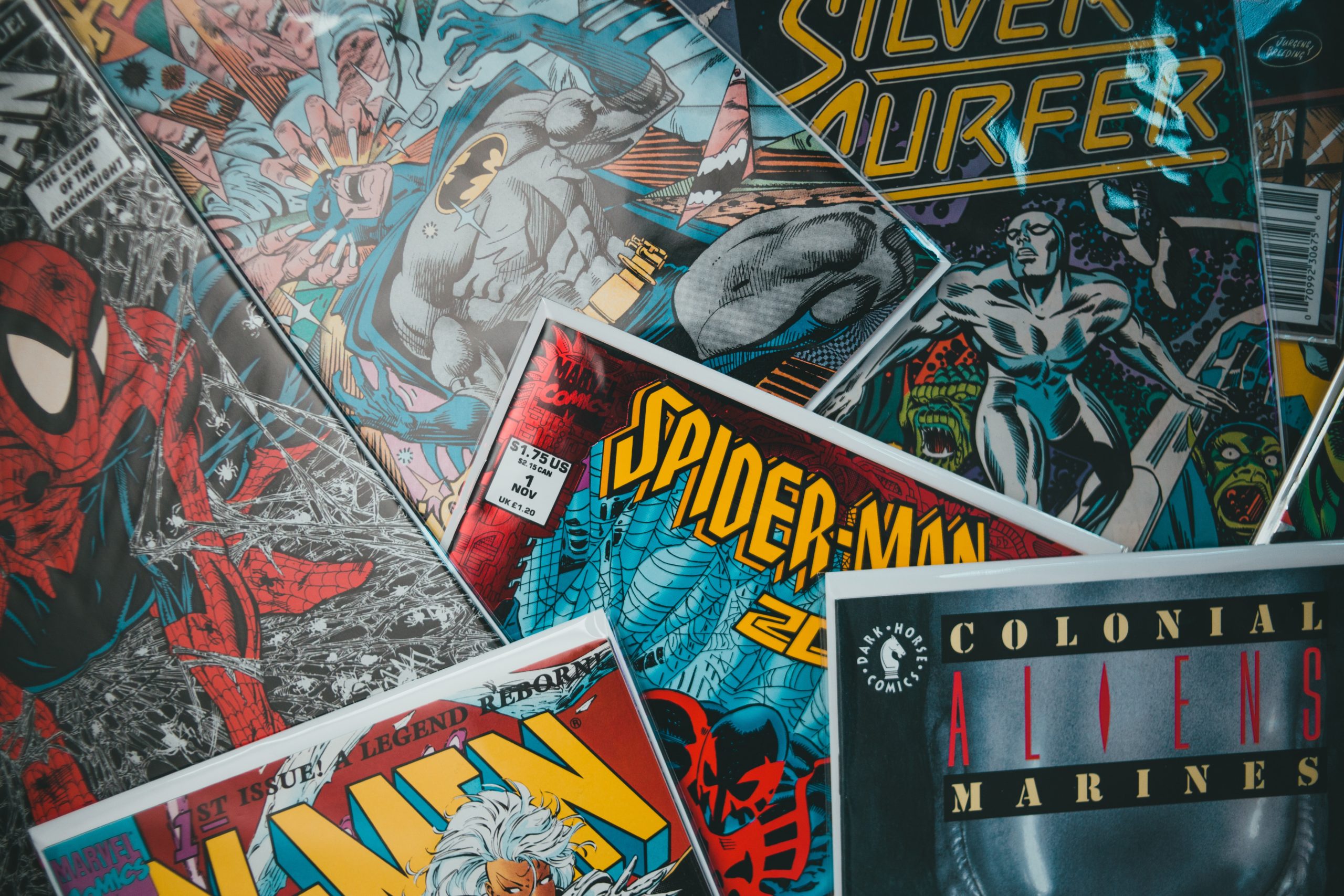 Diversas histórias em quadrinhos se empilham umas sobre as outras. Entre as obras, estão quadrinhos do Homem-Aranha, X-Men e Surfista Prateado