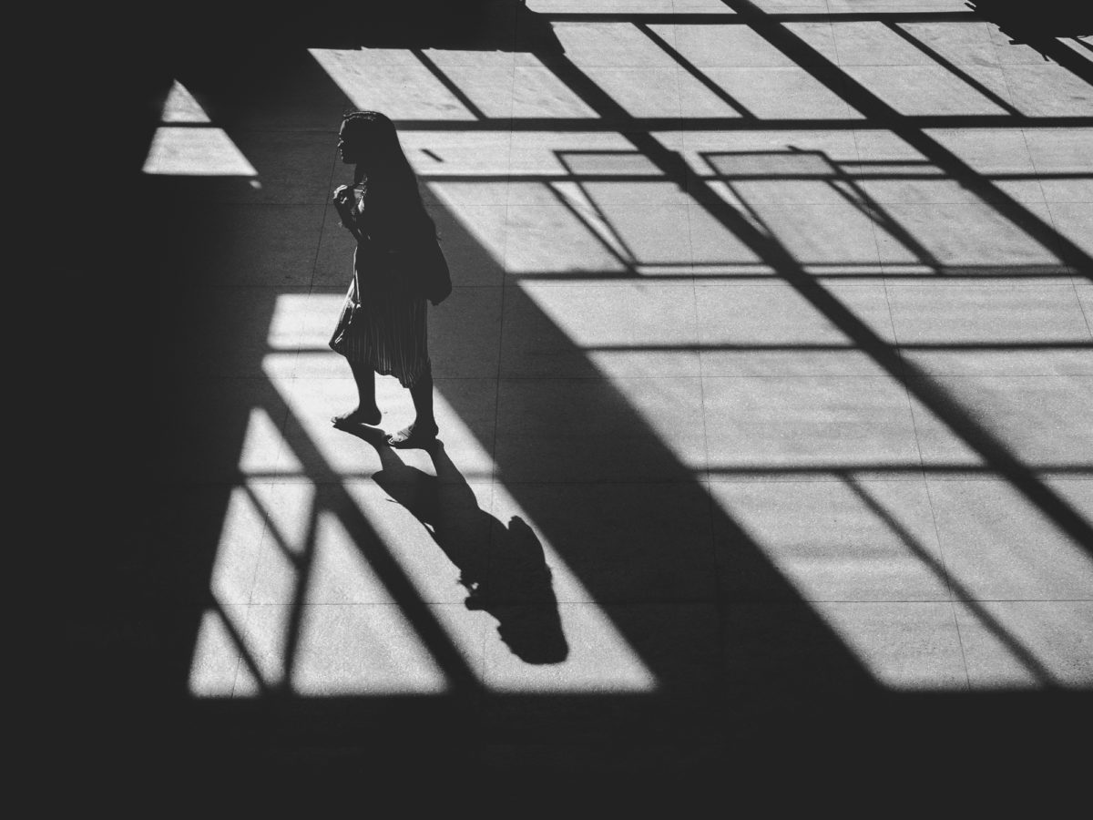 Uma mulher caminha em meio às sombras do Centro de Tecnologia