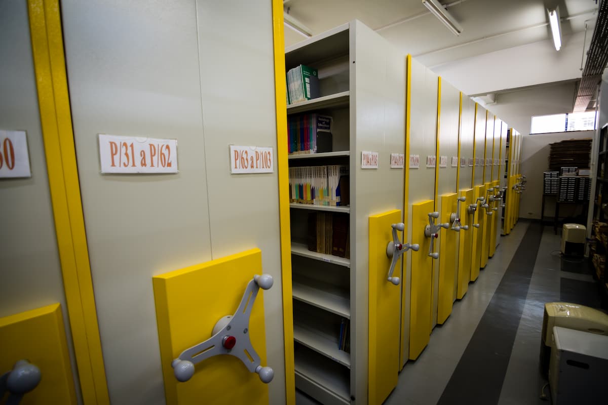 Fotografia mostra armários corta-fogo enfileirados. Um deles está aberto e é possível ver uma estante cheia de livros