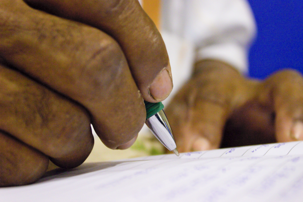 A mão de uma pessoa negra escreve em um papel