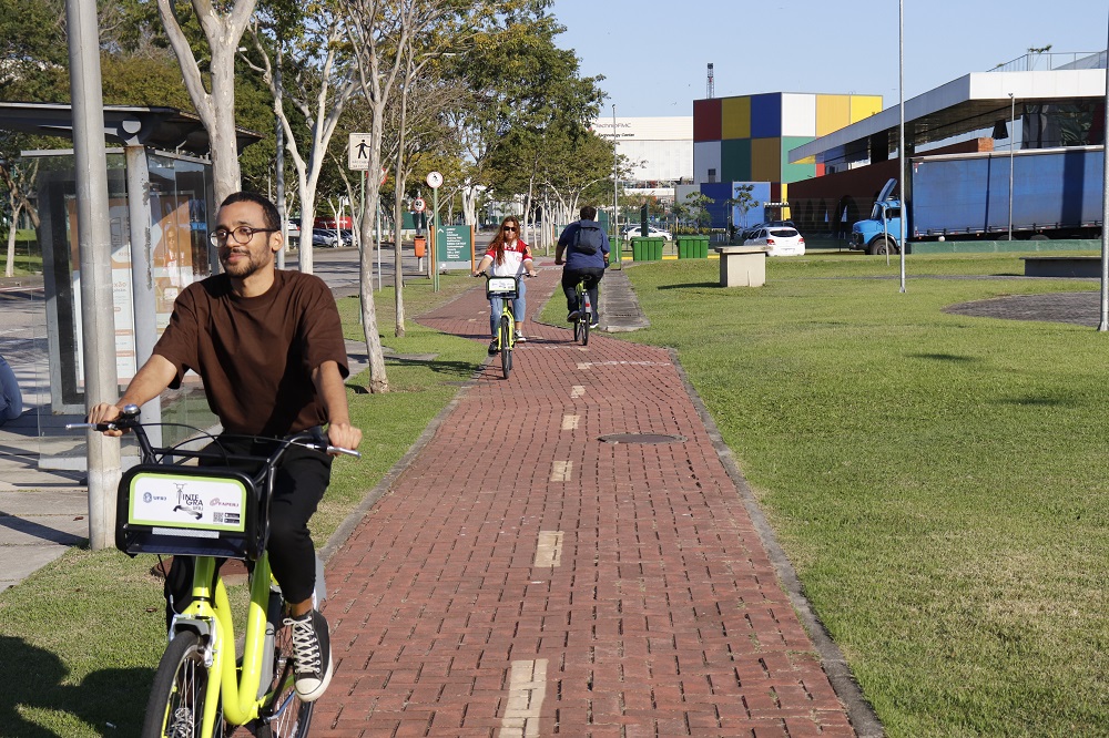Em uma ciclovia da Cidade Universitária, um jovem negro pedala uma das bicicletas do projeto