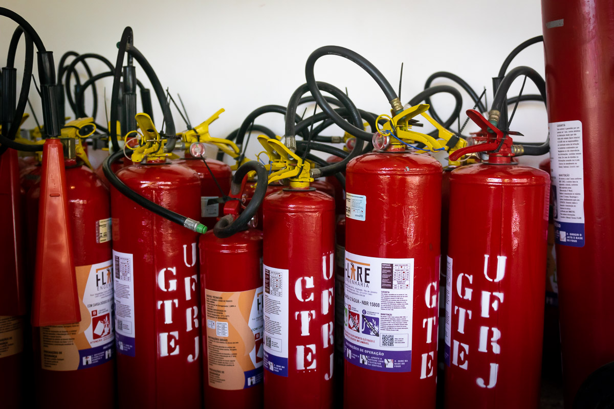 Diversos extintores de incêndio na cor vermelha estão agrupados.