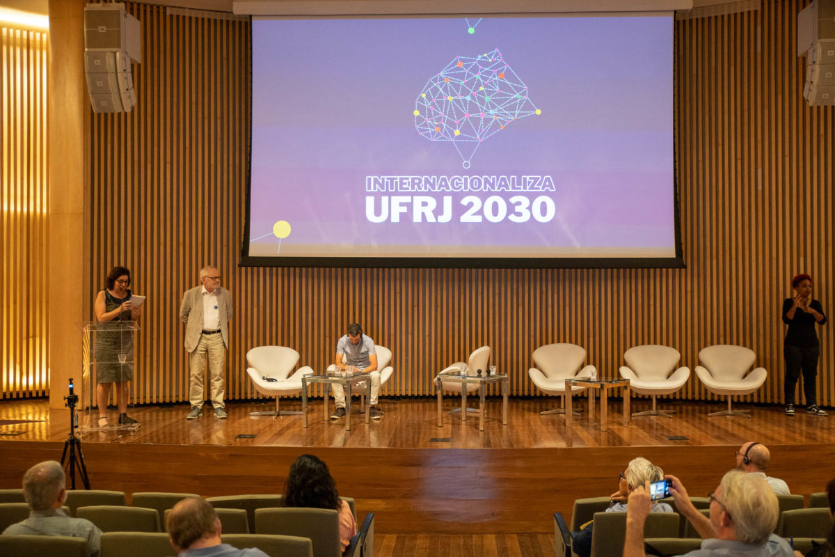 Auditório com projeção que apresenta o texto Internacionaliza UFRJ 2030