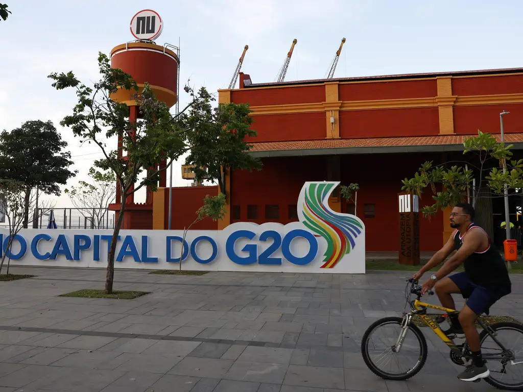 Fotografia mostra, ao fundo, um armazém na Zona Portuária do Rio de Janeiro. Em primeiro plano, grande painel horizontal no qual se lê “Capital do G20”.