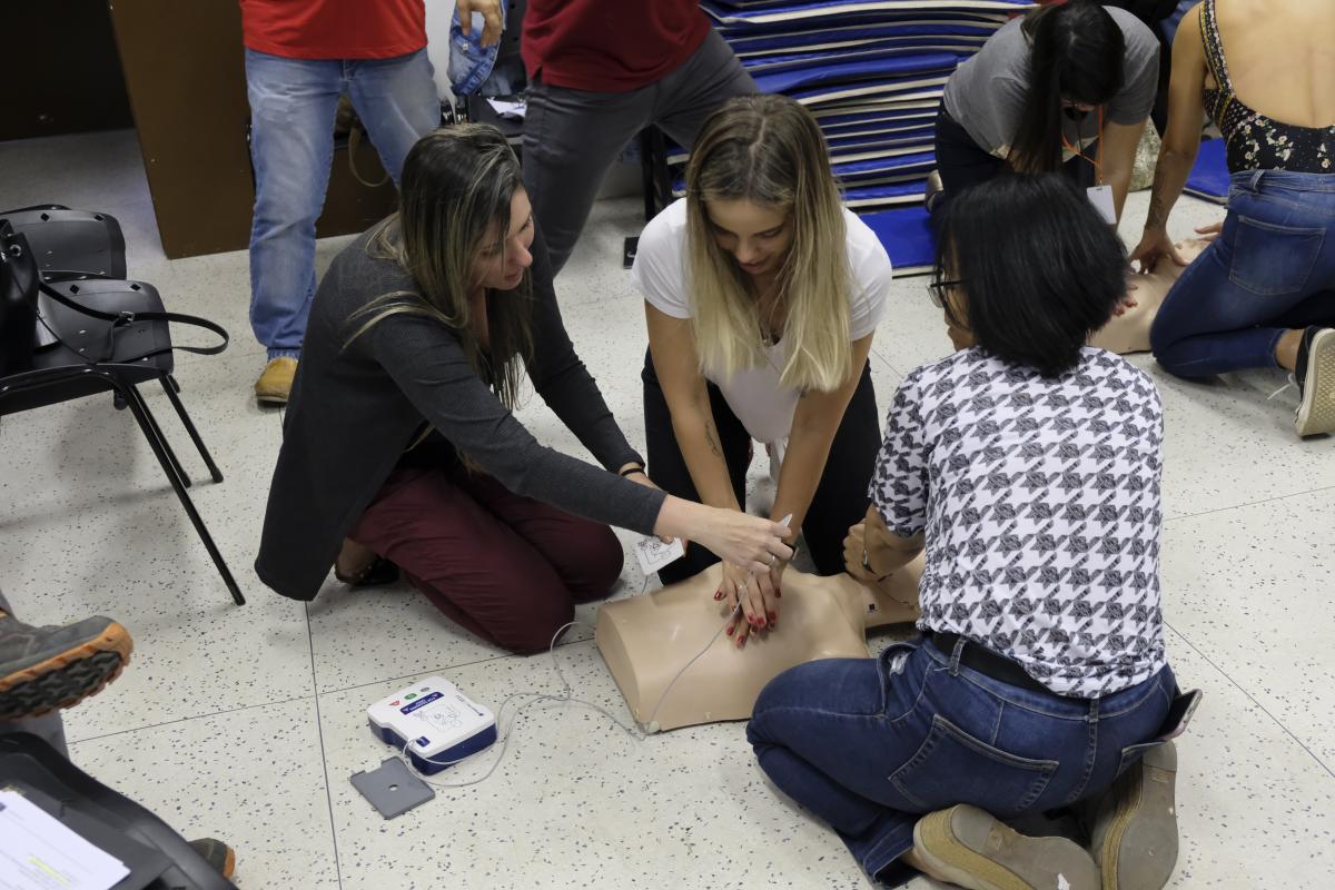 Participantes de curso realizam simulação de massagem cardíaca com boneco de treinamento.