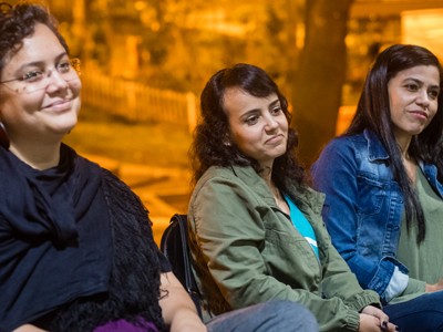 Três mulheres sentadas sorriem, durante o debate no cineclube Subúrbio em Transe