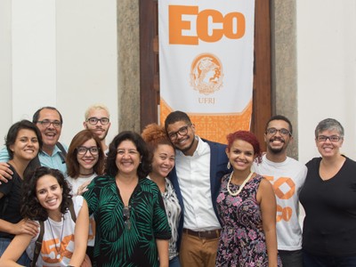 Imagem de Cristina Rego Monteiro, vice-diretora do departamento de jornalismo, e o diretor da ECO Amaury Fernandes com ex-alunos e organizadores do evento.