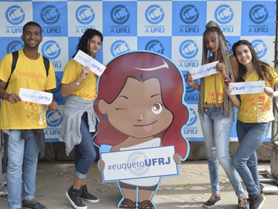 Imagem colorida de estudantes que seguram pequenos banners com a hashtag #euqueroUFRJ.
