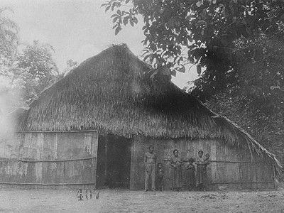 Foto antiga e em preto e branco de família na porta da tapera. Indígenas do Alto Rio Negro. Lugar em que o etnólogo Curt Nimuendajú esteve em 1927.