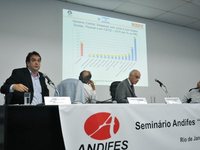 Imagem de Fernando Sarti, diretor do Instituto de Economia da Unicamp, mostrando gráfico com as altas despesas do governo com juros.