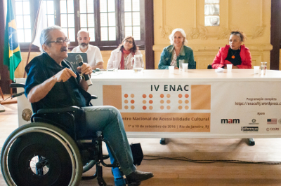 Foto de pessoa com deficiência discursando durante o Encontro Nacional de Acessibilidade Cultural, realizado na UFRJ entre os dias primeiro e dez de setembro.