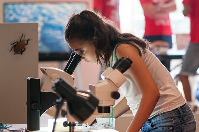 Uma jovem se posiciona diante do aparelho microscópio e vê outra imagem